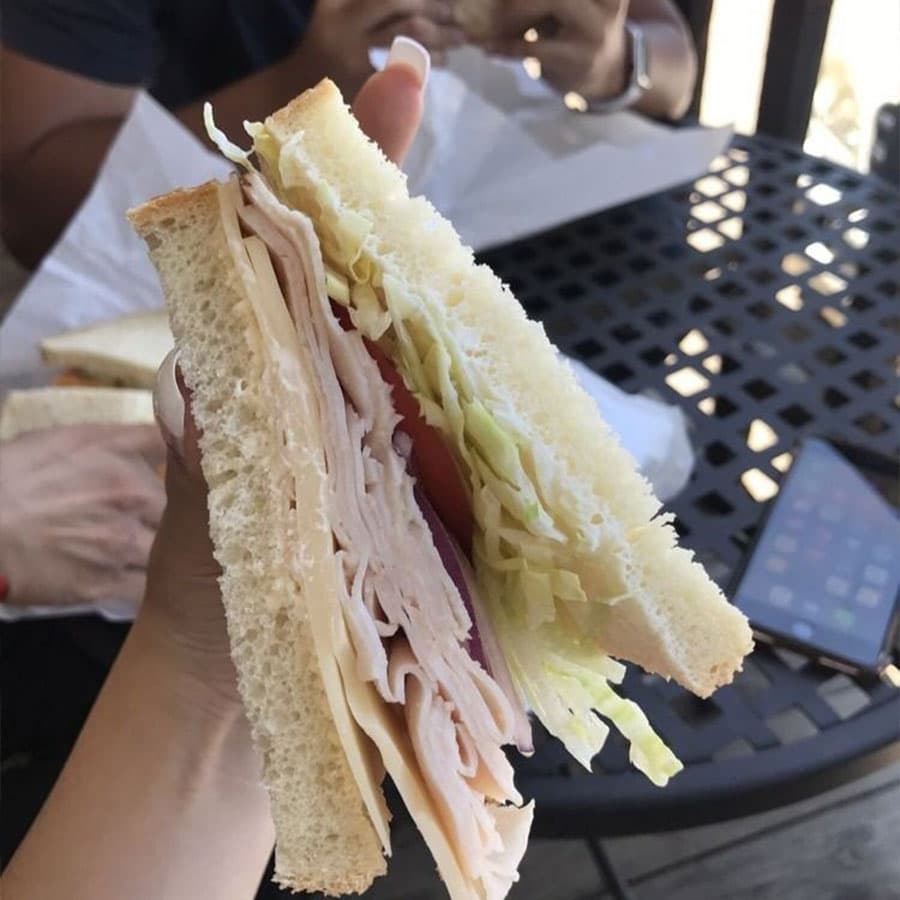 A close-up of a turkey and cheese sandwich on white bread.