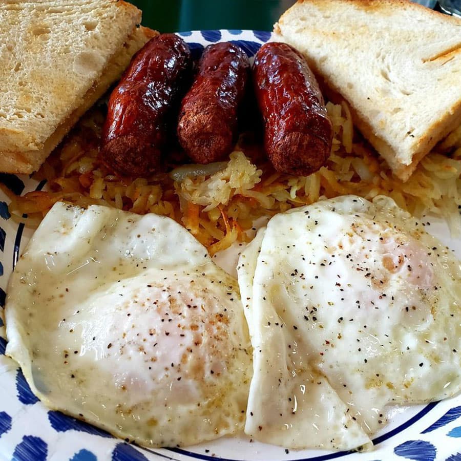 A breakfast plate with eggs, sausage, hash browns, and toast.
