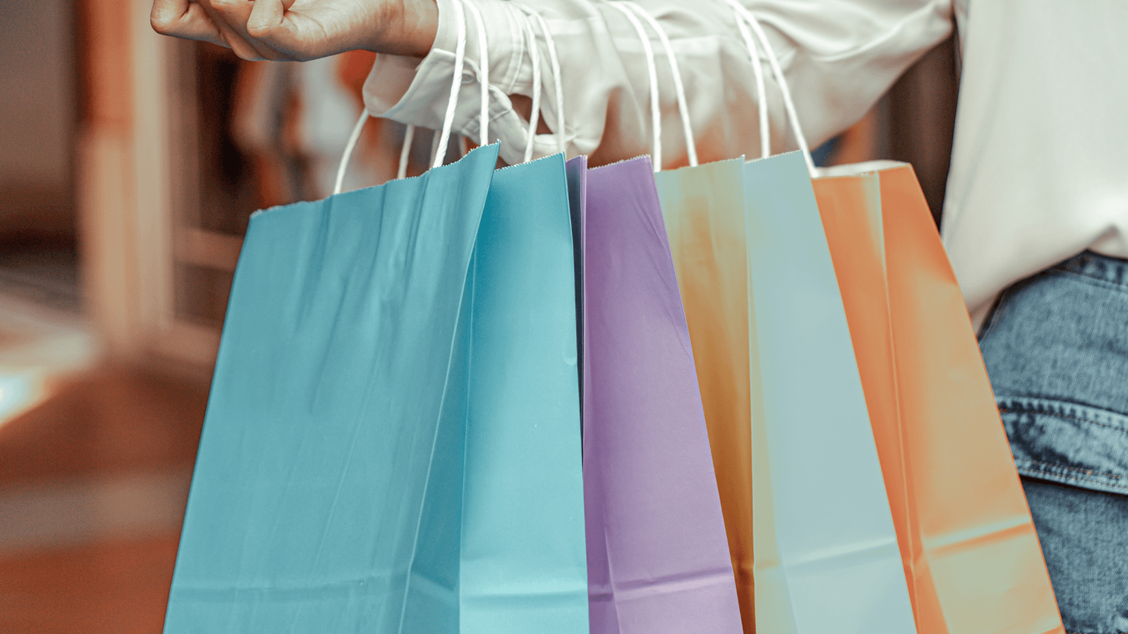 A person holds multiple colorful shopping bags.