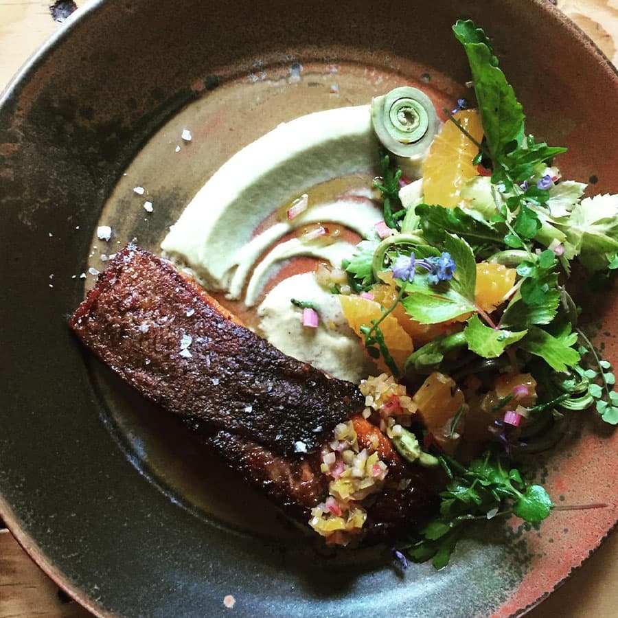 A crispy skin salmon fillet served with a citrus salad and a side of mashed potatoes.