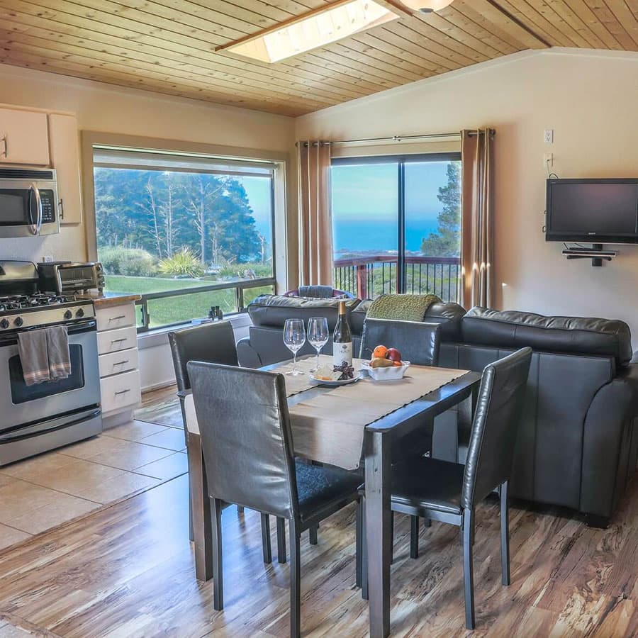 A comfortable living space with a dining table set for two, overlooking the beautiful Pacific Coast.