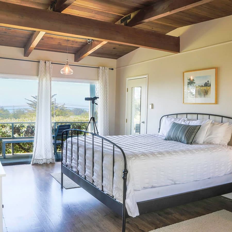 A spacious bedroom with a king-size bed, large windows offering stunning ocean views, and a private balcony.