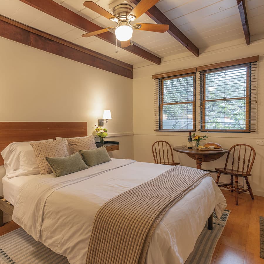 Cozy bedroom with a queen-size bed, wooden chairs, and a small table.