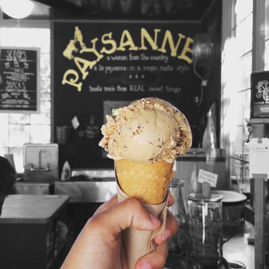 A person enjoying a scoop of caramel pecan ice cream in a waffle cone.