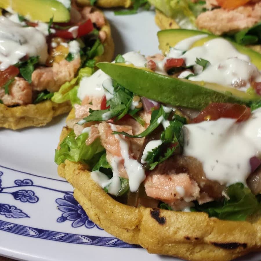 Plate of Boont Burger topped with melted cheese, fresh greens, and a side of crispy fries on a rustic wooden table at Boonville Hotel