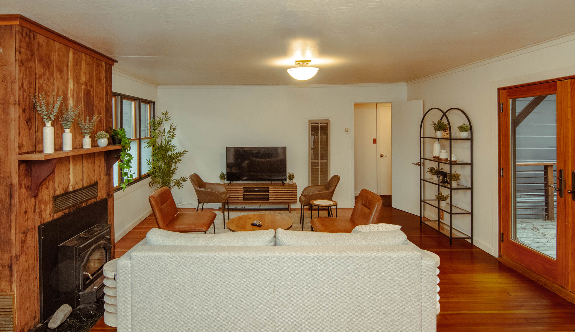 A cozy living room featuring a white sofa, leather chairs, a TV unit, and wooden accents.